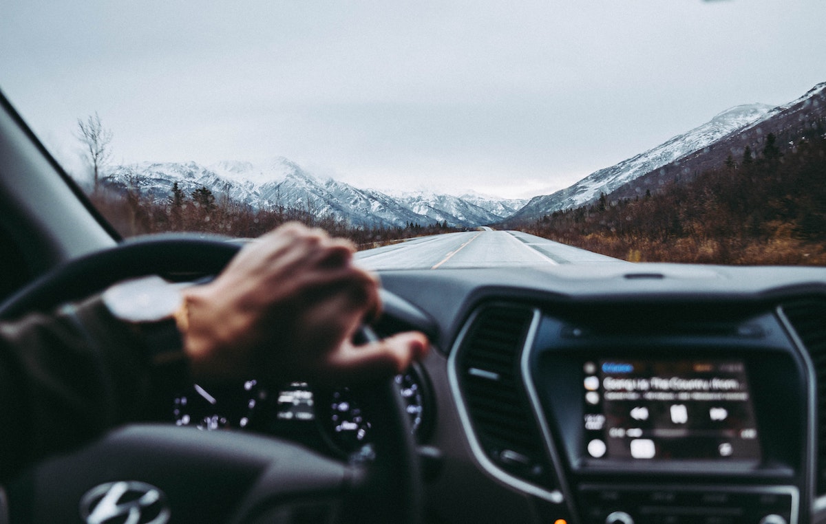 man driving car with view of the mountains thinking about extended car warranty